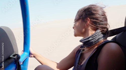 Close-up slow motion portrait of smiling young woman traveling in dune buggy at desert, she smiling while enjoying safari - Huacachina, Peru