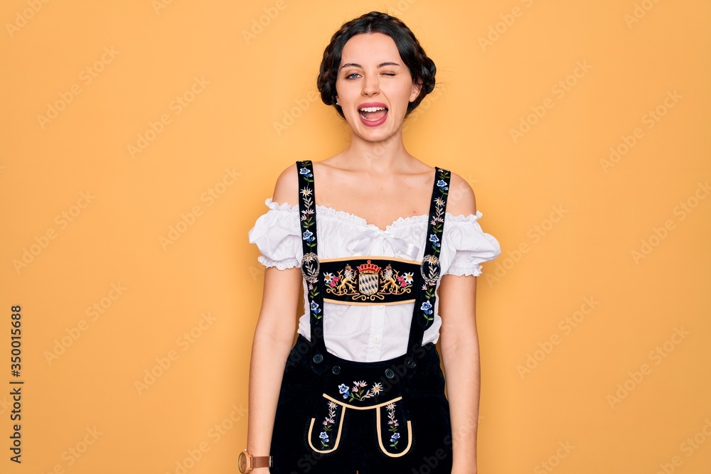 Young beautiful german woman with blue eyes wearing traditional octoberfest dress winking looking at the camera with sexy expression, cheerful and happy face. Young beautiful german woman with blue eyes wearing traditional octoberfest dress winking looking at the camera with sexy expression, cheerful and happy face.