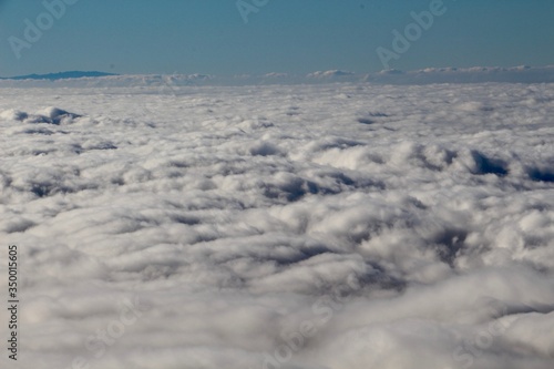 Aerial photo of a continuous sea of clouds seen from above taken from Mount Teide in the Canary Islands showing an almost infinite surface of clouds illuminated by the sun and under a blue sky