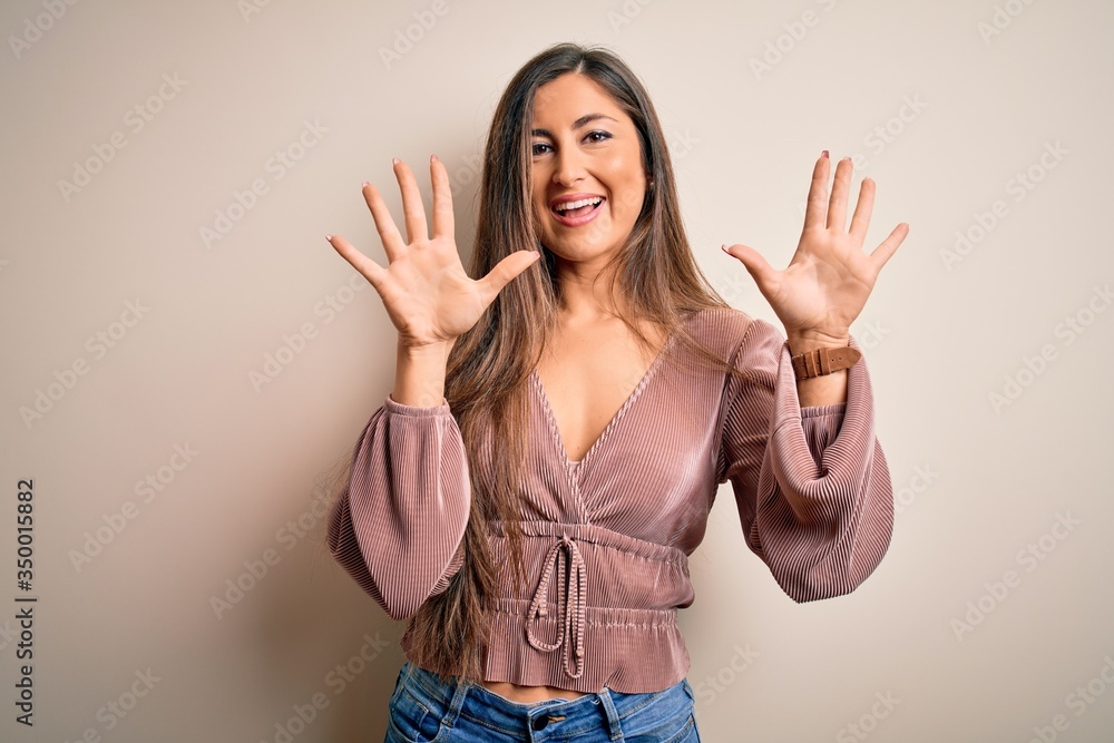 Young beautiful brunette elegant woman with long hair standing over isolated background showing and pointing up with fingers number ten while smiling confident and happy. Young beautiful brunette elegant woman with long hair standing over isolated background showing and pointing up with fingers number ten while smiling confident and happy.