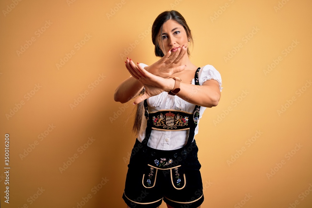 Young beautiful brunette german woman celebrating Octoberfest wearing traditional dress Rejection expression crossing arms and palms doing negative sign, angry face Young beautiful brunette german woman celebrating Octoberfest wearing traditional dress Rejection expression crossing arms and palms doing negative sign, angry face