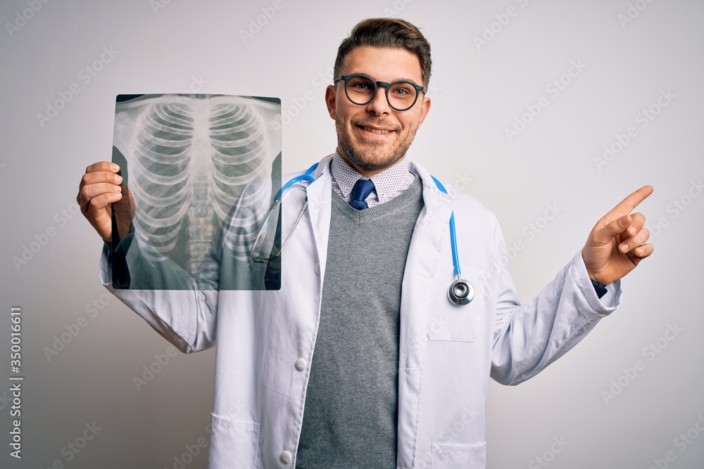 Young doctor man wearing medical coat looking at chest scan radiography over isolated background very happy pointing with hand and finger to the side Young doctor man wearing medical coat looking at chest scan radiography over isolated background very happy pointing with hand and finger to the side