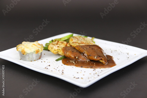 Grilled Chicken Breasts with Black Pepper Sauce served in white ceramic dish