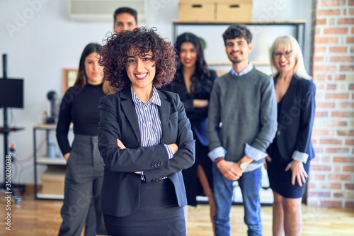 Group of business workers smiling happy and confident. Posing together with smile on face looking at the camera, young beautiful woman with crossed arms at the office