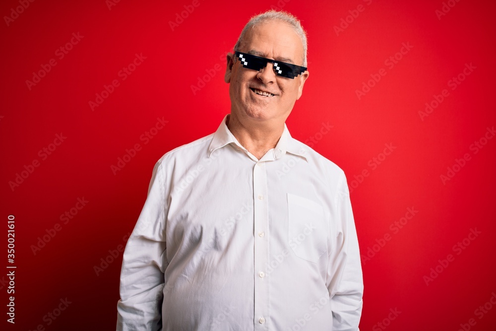 Middle age hoary man wearing funny sunglasses over isolated red background with a happy and cool smile on face. Lucky person. Middle age hoary man wearing funny sunglasses over isolated red background with a happy and cool smile on face. Lucky person.