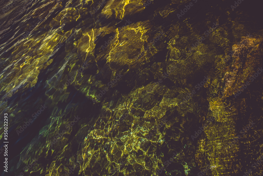 beautiful lagoon with clear water, moss rocks and green foliage in the background 