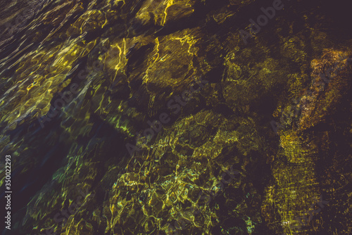 beautiful lagoon with clear water, moss rocks and green foliage in the background 