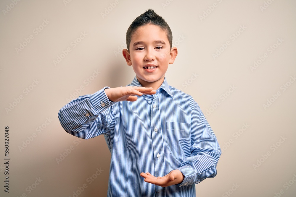 Young little boy kid wearing elegant shirt standing over isolated background gesturing with hands showing big and large size sign, measure symbol. Smiling looking at the camera. Measuring concept. Young little boy kid wearing elegant shirt standing over isolated background gesturing with hands showing big and large size sign, measure symbol. Smiling looking at the camera. Measuring concept.