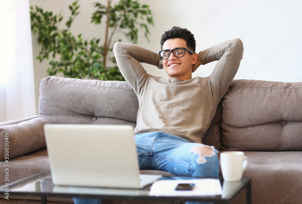 Ethnic freelancer resting on sofa after finishing project. Ethnic freelancer resting on sofa after finishing project.
