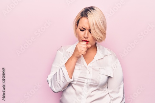 Young beautiful blonde plus size woman wearing elegant shirt over isolated pink background feeling unwell and coughing as symptom for cold or bronchitis. Health care concept. © Krakenimages.com