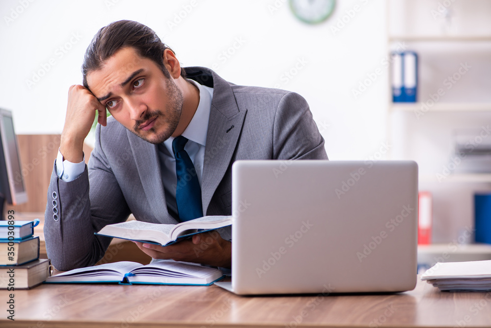 Young male businessman reading books at workplace Young male businessman reading books at workplace