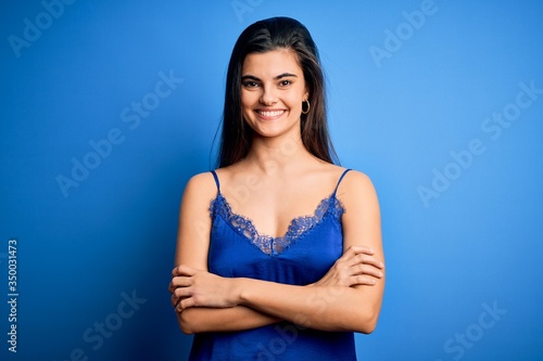 Young beautiful brunette woman wearing elegant and comfortable blue lingerie underwear happy face smiling with crossed arms looking at the camera. Positive person.