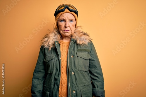 Senior beautiful grey-haired skier woman wearing snow sportswear and ski goggles depressed and worry for distress, crying angry and afraid. Sad expression.