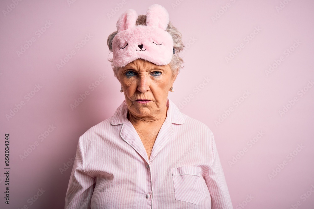 Senior beautiful woman wearing sleep mask and pajama over isolated pink background skeptic and nervous, frowning upset because of problem. Negative person. Senior beautiful woman wearing sleep mask and pajama over isolated pink background skeptic and nervous, frowning upset because of problem. Negative person.