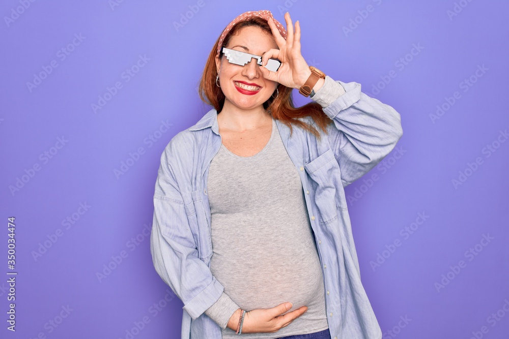 Φωτογραφία Young redhead pregnant woman expecting baby wearing funny thug life sunglasses doing ok gesture with hand smiling, eye looking through fingers with happy face