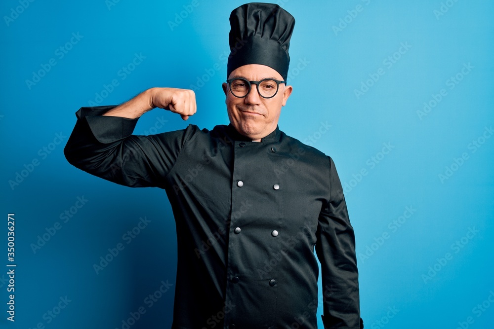 Middle age handsome grey-haired chef man wearing cooker uniform and hat Strong person showing arm muscle, confident and proud of power Middle age handsome grey-haired chef man wearing cooker uniform and hat Strong person showing arm muscle, confident and proud of power