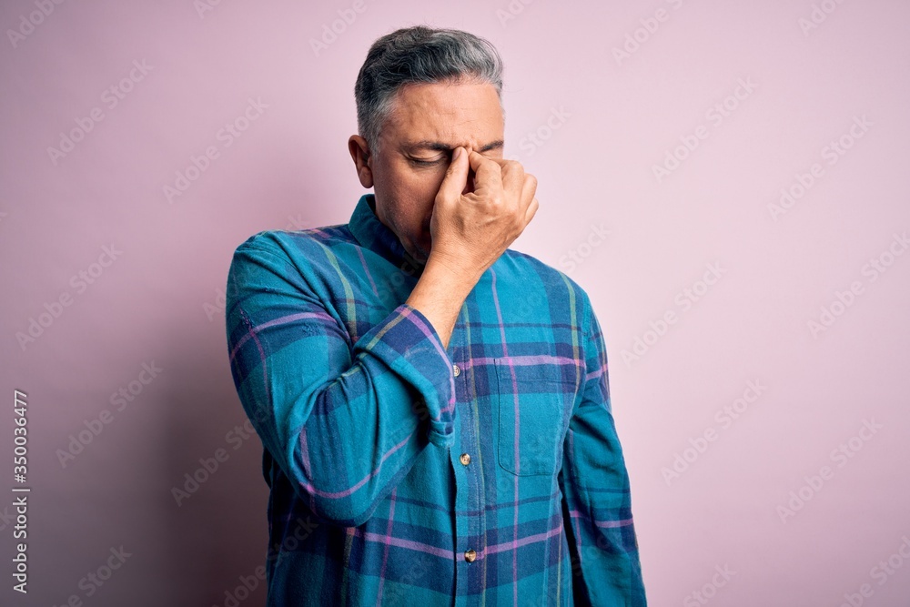 Middle age handsome grey-haired man wearing casual shirt over isolated pink background tired rubbing nose and eyes feeling fatigue and headache. Stress and frustration concept. Middle age handsome grey-haired man wearing casual shirt over isolated pink background tired rubbing nose and eyes feeling fatigue and headache. Stress and frustration concept.