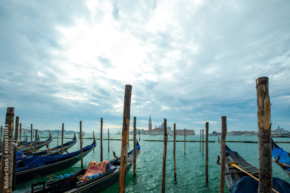 Photograph of Gondola's docked on the shore of Venice, Italy. Cloudy overcast day.