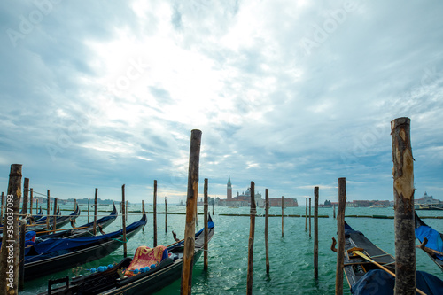 Photograph of Gondola's docked on the shore of Venice, Italy. Cloudy overcast day.