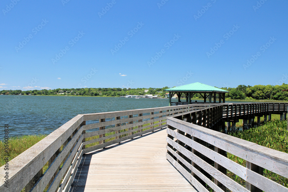 Obraz premium Wooden boardwalk during sunny summer with lake view