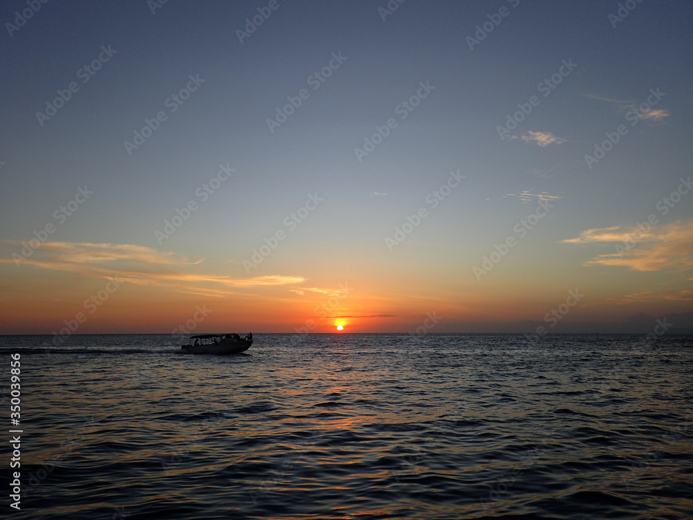 Fototapeta premium ボルネオの夕日の海を走るボート