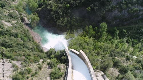 AERIAL DRONE FORWARD FOLLOWING WATER FLOWING IN OPEN DAM GATE AND TOP-DOWN END OF WATERFALL 