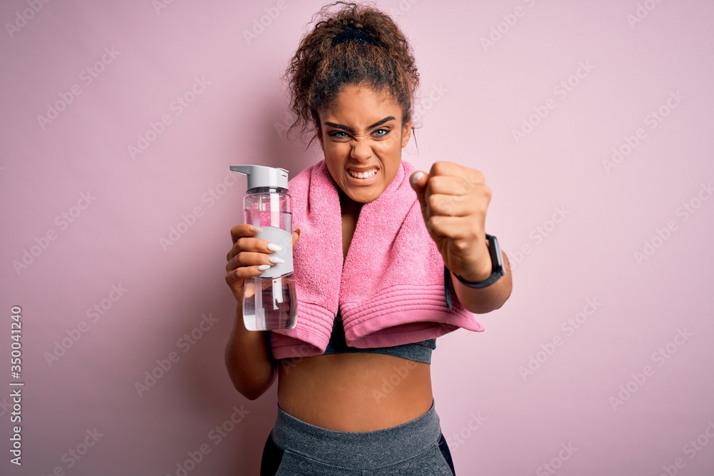 Young african american sporty girl doing sport wearing towel drinking bottle of water annoyed and frustrated shouting with anger, crazy and yelling with raised hand, anger concept Young african american sporty girl doing sport wearing towel drinking bottle of water annoyed and frustrated shouting with anger, crazy and yelling with raised hand, anger concept
