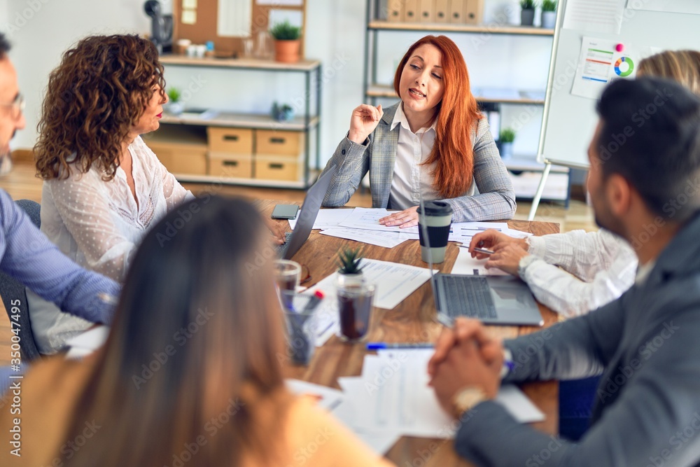 Group of business workers working together. Sitting on desk using laptop reading documents at the office Group of business workers working together. Sitting on desk using laptop reading documents at the office