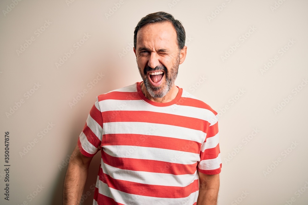Middle age hoary man wearing casual striped t-shirt standing over isolated white background winking looking at the camera with sexy expression, cheerful and happy face. Middle age hoary man wearing casual striped t-shirt standing over isolated white background winking looking at the camera with sexy expression, cheerful and happy face.