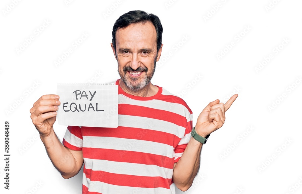 Middle age handsome man asking for social rights holding paper with pay equal message smiling happy pointing with hand and finger to the side Middle age handsome man asking for social rights holding paper with pay equal message smiling happy pointing with hand and finger to the side