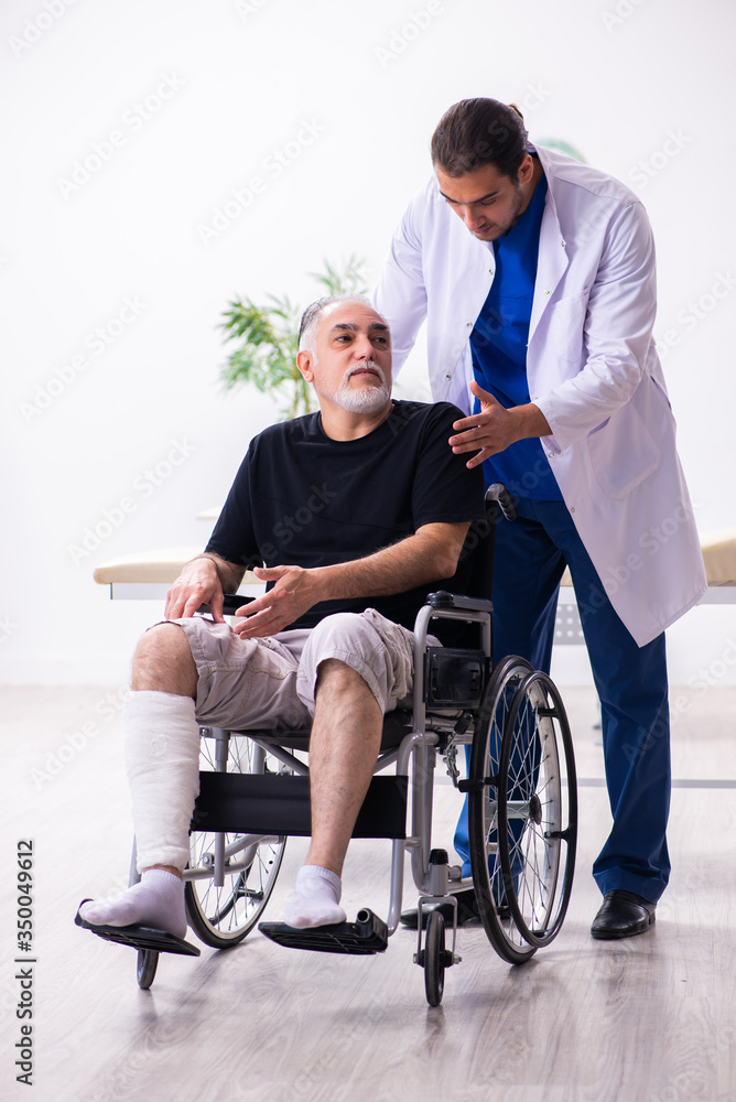 Old injured man visiting young male doctor traumatologist Old injured man visiting young male doctor traumatologist