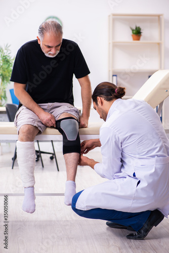 Old injured man visiting young male doctor traumatologist