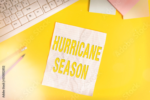 Word writing text Hurricane Season. Business photo showcasing time when most tropical cyclones are expected to develop Copy space on notebook above yellow background with pc keyboard on the table photo