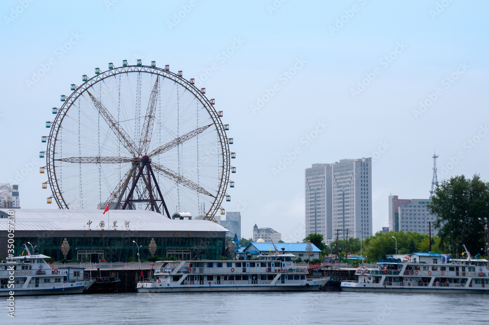 China, Heihe, July 2019: River station and Ferris wheel on the banks of the Amur river near the city of Heihe in summer