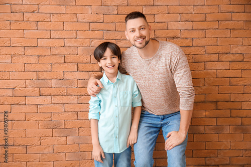 Father and little son on brick background