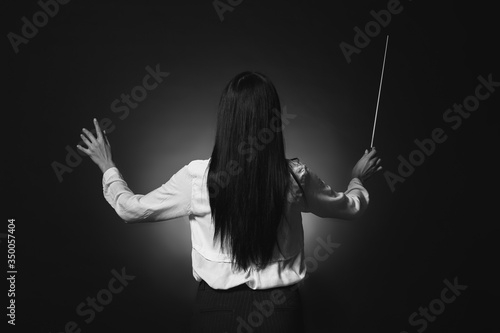 Black and white photo of young female conductor on dark background