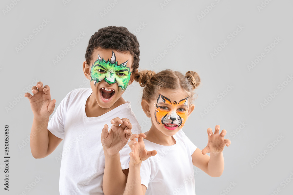 Funny children with face painting on light background Funny children with face painting on light background
