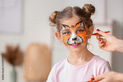 Woman painting face of litt...