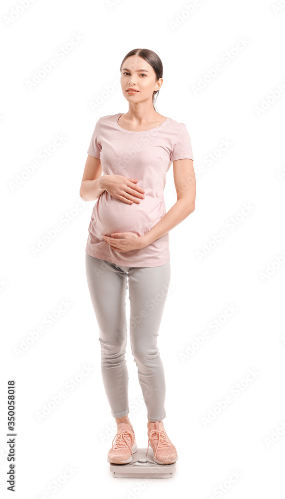 Young pregnant woman measuring her weight on white background Young pregnant woman measuring her weight on white background