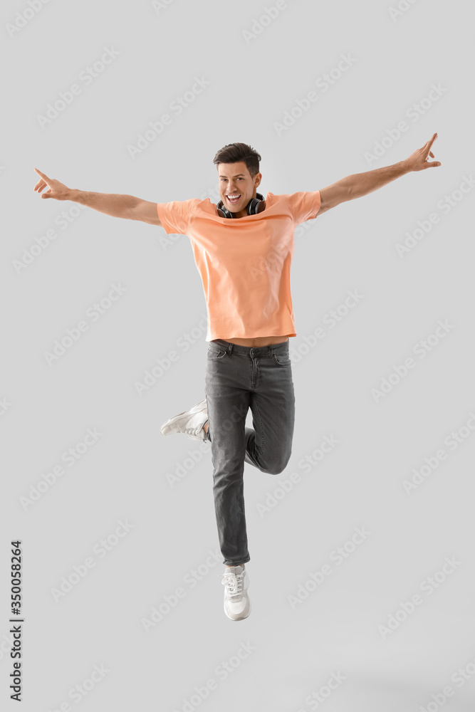 Handsome young man jumping against light background Handsome young man jumping against light background