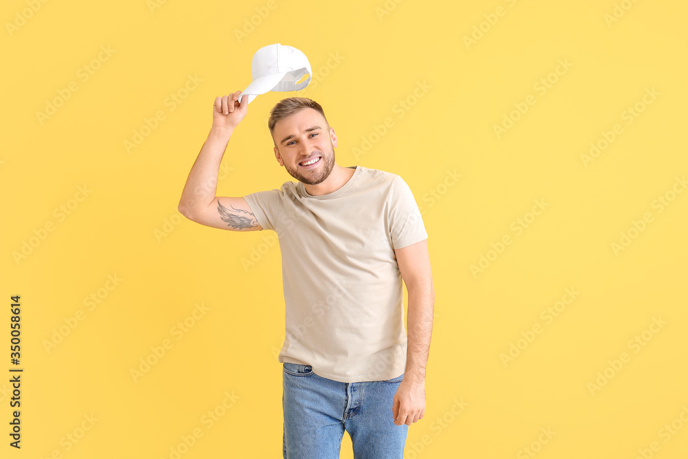 Handsome man in stylish cap on color background