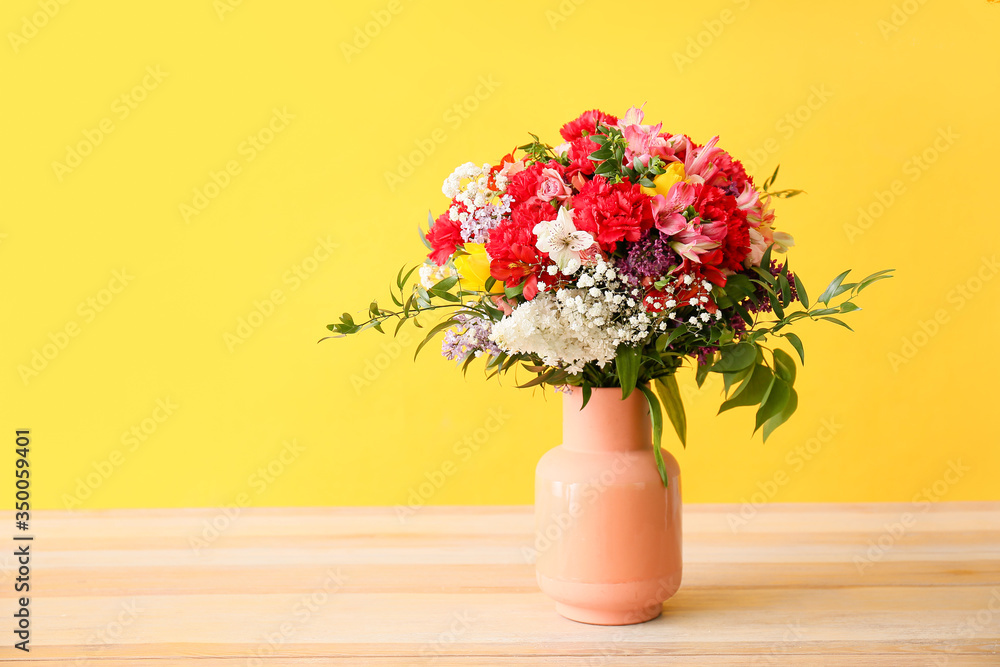 Vase with bouquet of beautiful flowers on table against color background