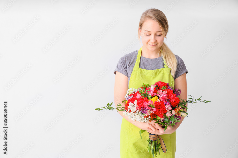Female florist with beautiful bouquet on light background Female florist with beautiful bouquet on light background