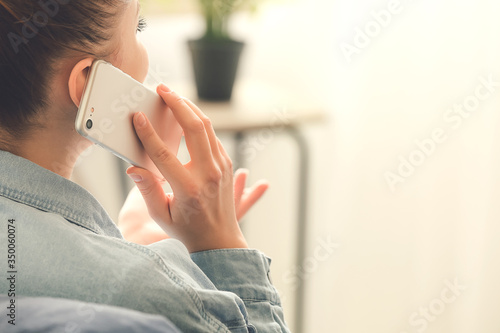 Woman talking by mobile phone at home photo