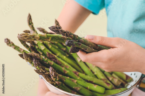 Woman with fresh asparagus on color background, closeup