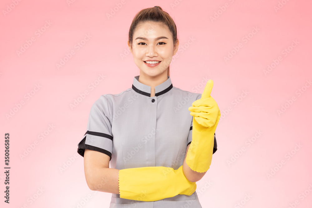 Attractive Beautiful Asian woman maid wearing gloves smile and thumbs up hand sign feeling so happiness and confident,Isolated on pink background,Cleaning Service concept Attractive Beautiful Asian woman maid wearing gloves smile and thumbs up hand sign feeling so happiness and confident,Isolated on pink background,Cleaning Service concept