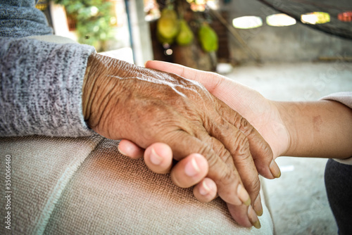 Close up granddaughter takes care of the health sick grandmother at home by holding hands. Lifestyle support the love of the family.