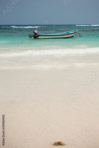 boat floating in a beautiful turquoise blue water caribbean beach in a sunny day with blue sky