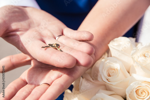 The hands of newlyweds hold the key to the lock of love, a symbol of a strong marriage. Wedding tradition. Hands of newlyweds close-up.