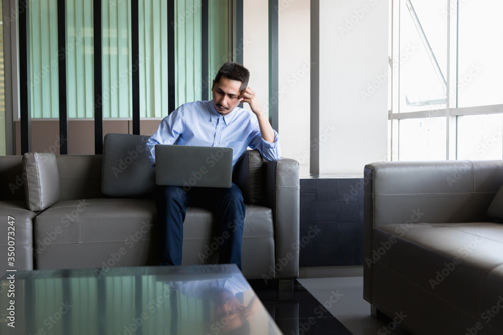 A young businessman using laptop working with happy on sofa in modern office. A young businessman using laptop working with happy on sofa in modern office.